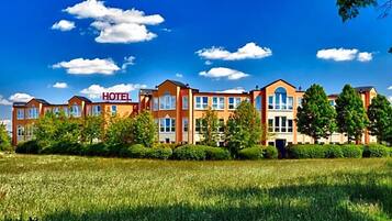 Ein Hotel mit mehreren Gebäuden, blauem Himmel und einem grünen Feld im Vordergrund.