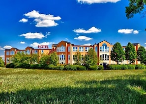 A hotel with multiple buildings, a clear sky, and a grassy field in the foreground. - Grunau (Bayreuth)