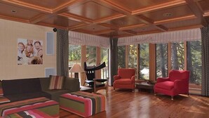 A spacious living room with wooden flooring, a large window with curtains, and a sofa with colorful cushions. - Luxury On Mountain Ski Accommodation located between Alta and Snowbird (Alta)