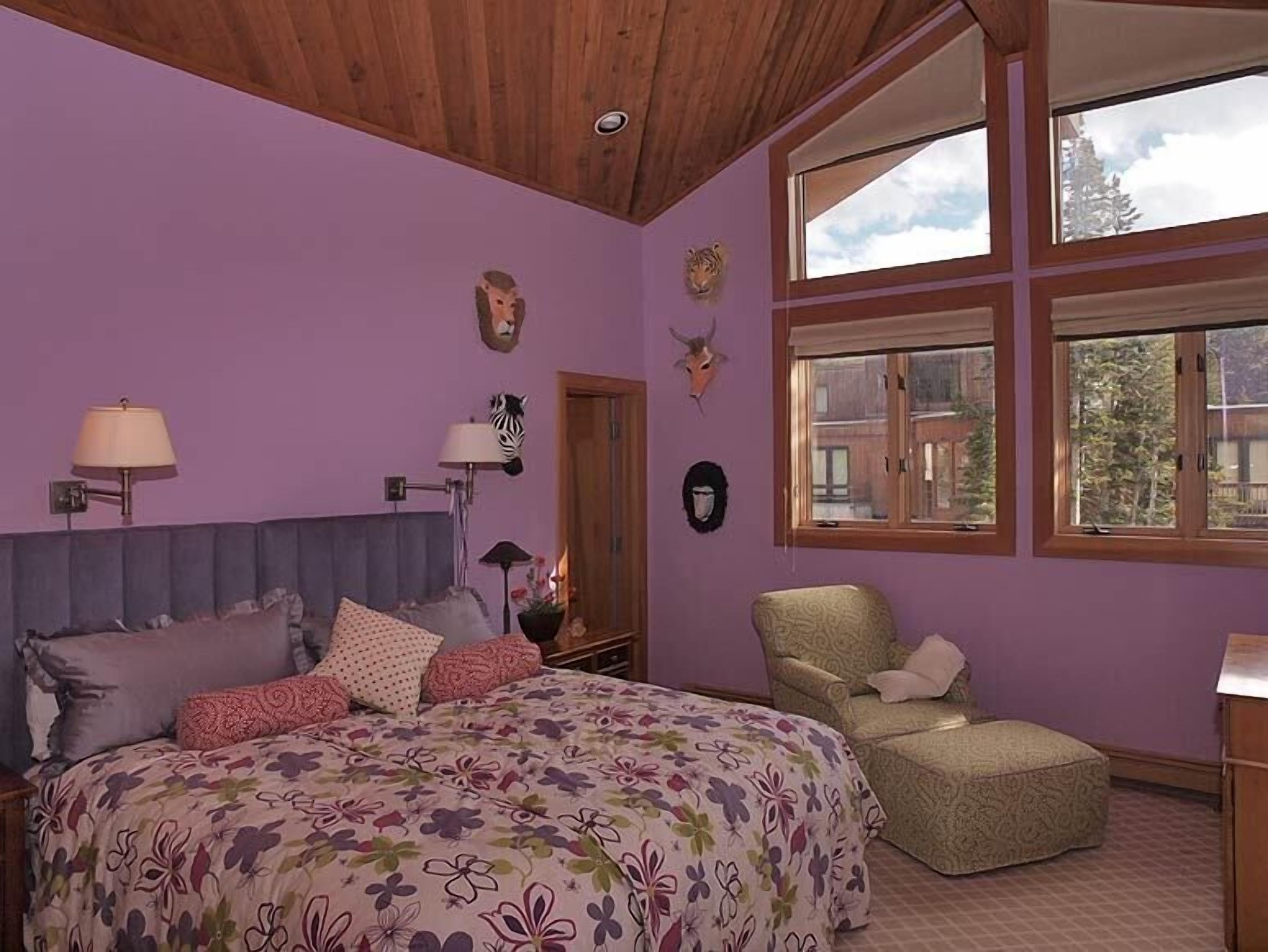 Une chambre à coucher avec un lit, une chaise et une fenêtre donnant sur des immeubles.