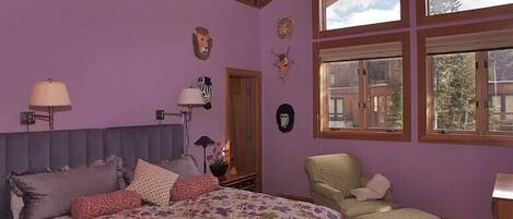 Une chambre à coucher avec un lit, une chaise et une fenêtre donnant sur des immeubles.