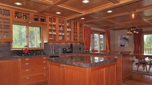 A spacious kitchen with wooden cabinetry, granite countertops, and a central island. - Luxury On Mountain Ski Accommodation located between Alta and Snowbird (Alta)