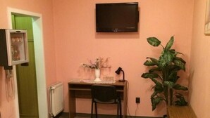 Una sala pequeña con un sofá verde, una mesa de madera, un televisor y una planta en maceta.