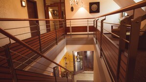 Una escalera de madera de varios niveles con barandillas de metal y un rellano alfombrado.