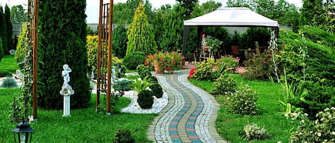 A garden with a stone pathway, a wooden pergola, and a gazebo.