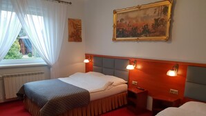 A hotel room with a bed, a nightstand, a lamp, a painting on the wall, and a window with curtains. - Hotel Hawana (Bydgoszcz)
