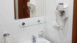 A bathroom with a white sink, a mirror, a hairdryer, and a towel rack. - Hotel Hawana (Bydgoszcz)