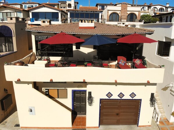 A two-story building with a terrace featuring outdoor seating and umbrellas.