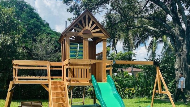 A wooden playground structure with a slide, climbing area, and a small house-like tower. - #6 Heated Pool, Private Patio & Grill, 1BR+sunroom (Fort Lauderdale)