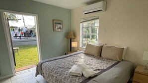 A bedroom with a bed, a nightstand, a lamp, a window, and a door leading to a balcony. - #6 Heated Pool, Private Patio & Grill, 1BR+sunroom (Fort Lauderdale)