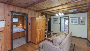 A wooden interior with a bed, wardrobe, sofa, and framed pictures on the walls.