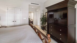 A bedroom with a bed, a dresser with a TV, and a ceiling fan.