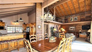 Ein geräumiger Essbereich mit Holztisch und -stühlen, einer Chandelierleuchtre und einer Küche im Hintergrund.