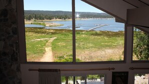 Ein Zimmer mit großem Fenster mit Blick auf einen See, einen Pfad und eine Anlegestelle.