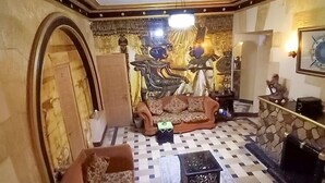 Ett vardagsrum med ett rutmönstrat golv, två soffor, ett soffbord och en dekorativ vägg med egyptiska motiv.