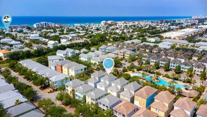Vue aérienne d’un quartier résidentiel situé sur la côte, avec une grande piscine et plusieurs immeubles d’appartements.