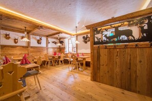 A rustic wooden interior with a dining area, wooden walls, and ceiling beams. - Hotel Tolderhof (San Candido)