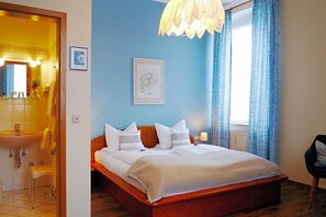 A bedroom with a wooden bed, a bedside table, a mirror, and a window with curtains.