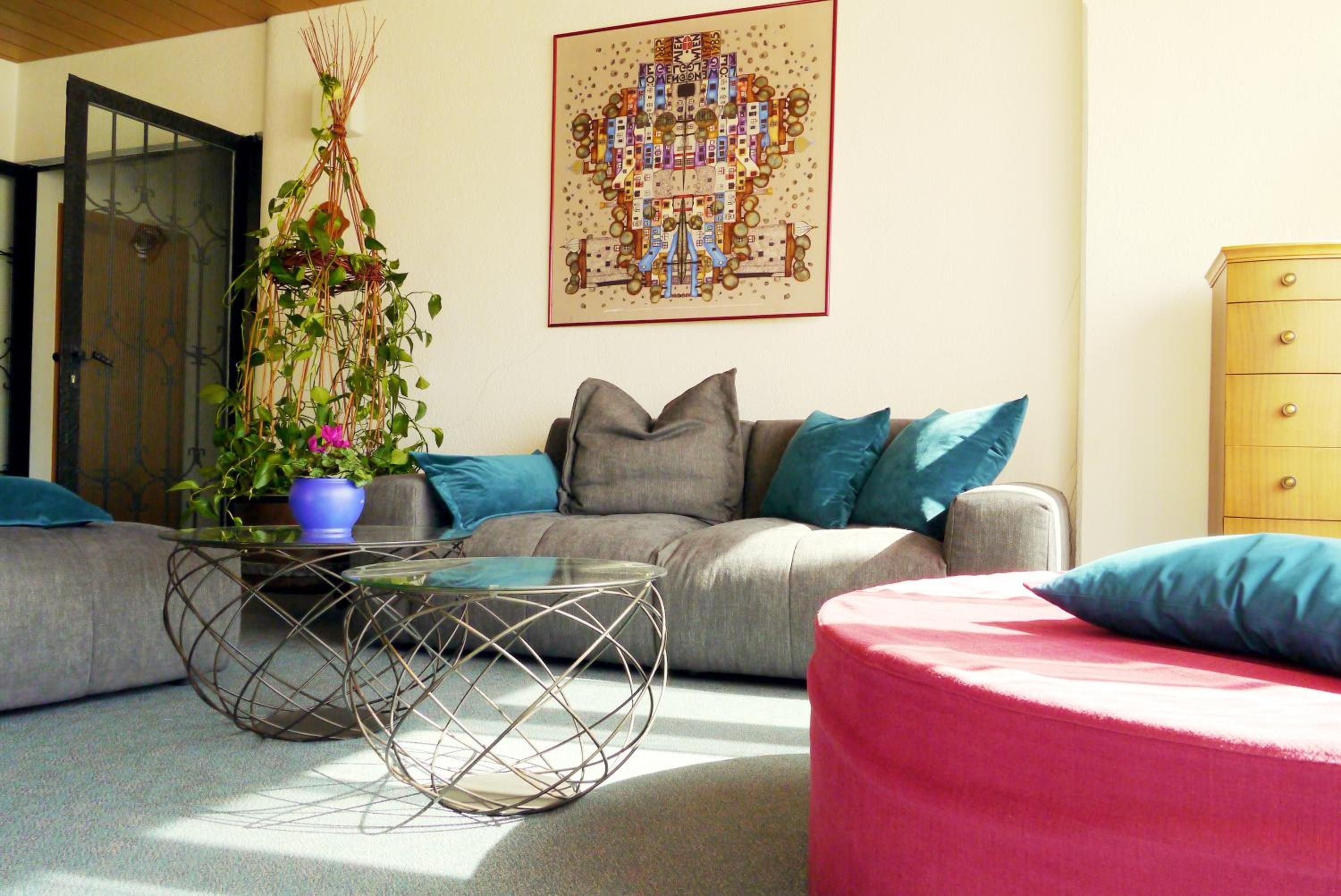 A living room with a grey sofa, a glass coffee table, and a potted plant.