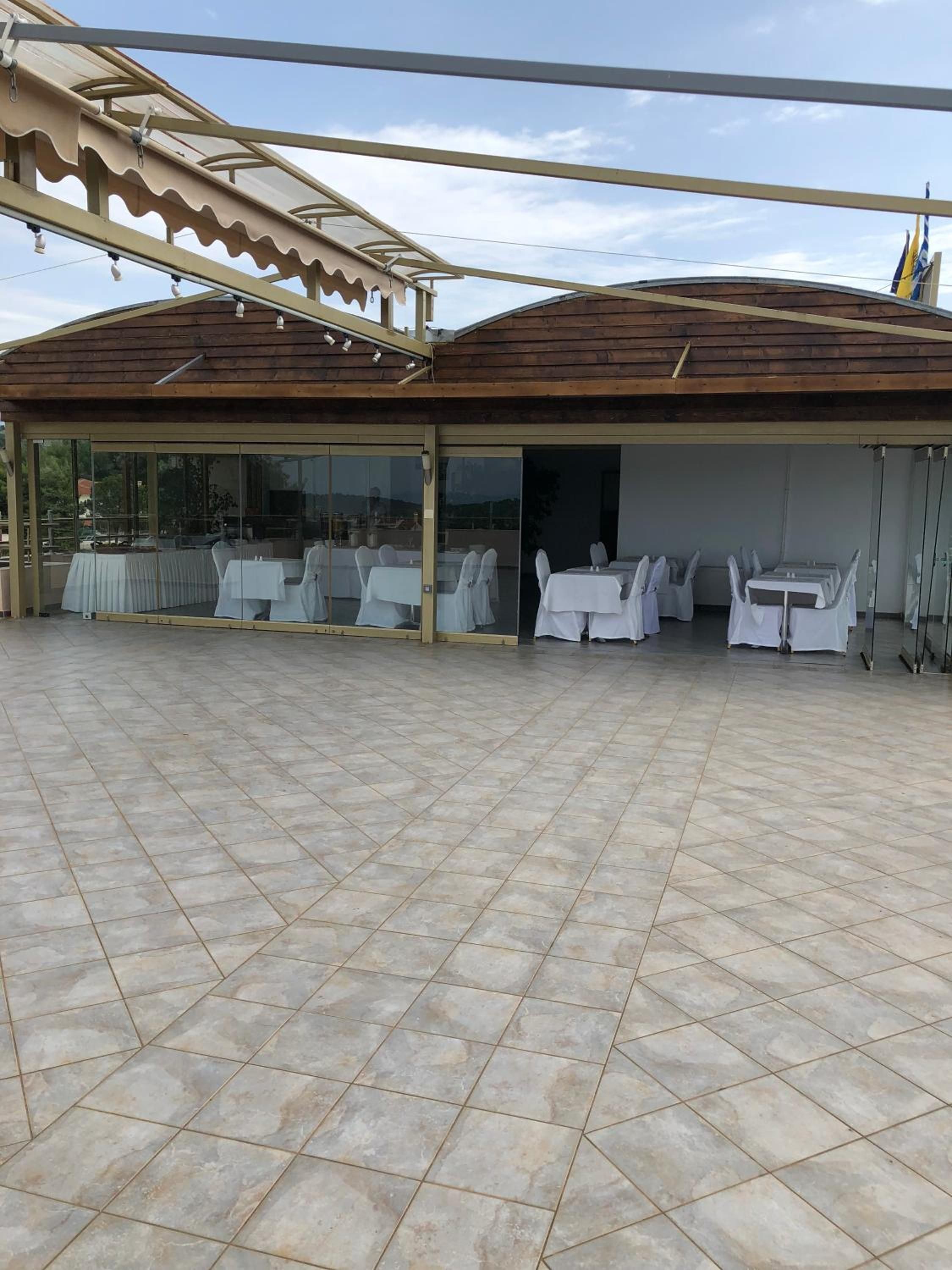 Une terrasse extérieure dotée d’un sol carrelé, d’espaces de repos couverts et d’une structure de toit en bois.