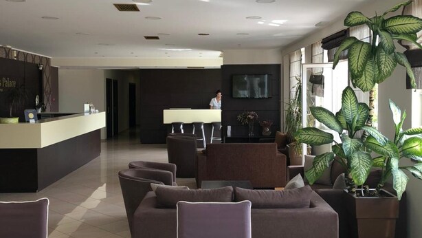 A hotel lobby with a reception desk, seating area, and large windows.