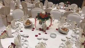 A round table set for a formal event with white tablecloths, glassware, and napkin holders.