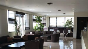 A spacious lobby with a seating area, large windows, and a reception desk.