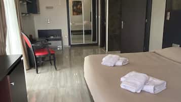 A hotel room with a bed, a desk, a chair, and a wardrobe.