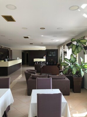 A hotel lobby with a reception desk, seating area, and large windows. - Selefkos Palace (Igoumenitsa)