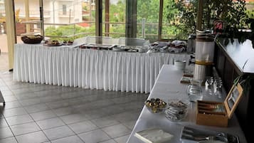 Un buffet est installé, avec une table recouverte d’une nappe blanche, des plats et des ustensiles de service.