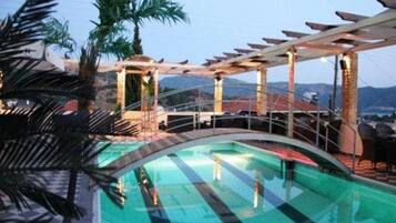 Une piscine sur le toit, agrémentée d’une pergola et de palmiers.