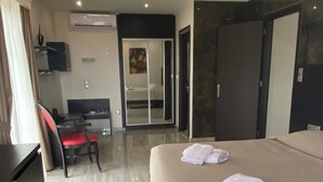 A hotel room with a bed, a desk, a chair, and a wardrobe.