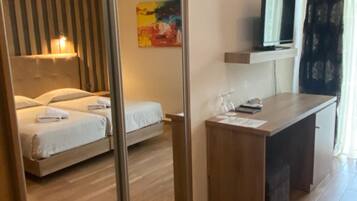 Une chambre d’hôtel avec un lit, un bureau, une télévision et un tableau au mur.