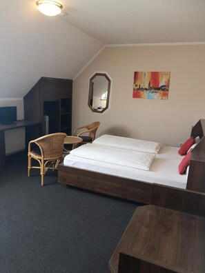 A bedroom with a bed, a desk, a chair, and a mirror.