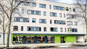 A modern hotel with a flat facade, multiple windows, and a green entrance. - B&B Hotel Bonn-West (Bonn)