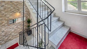 A staircase with a stone wall and a red carpeted landing. - Hotel Restaurant Mathildenhof (Pulheim)