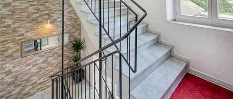 Un escalier avec un mur en pierre et une plateforme recouverte d’une moquette rouge.