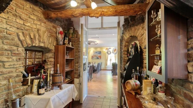 A rustic interior with stone walls, wooden beams, and a bar area with bottles and glasses. - Hotel Restaurant Mathildenhof (Pulheim)