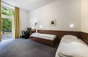 A hotel room with a bed, a desk, and a chair. There are two bedside lamps and a window with curtains. - CJD Bonn (Bonn)