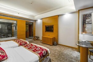 Una habitación de hotel con dos camas, un armario de madera, un televisor y un cuadro en la pared.