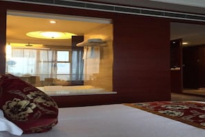 A hotel room with a bed, a window, and a view of another room. - Guest Hotel of Luohe (Luohe)