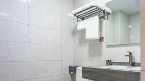 Een moderne badkamer met toilet, wastafel, spiegel, handdoekrek en handdroger.