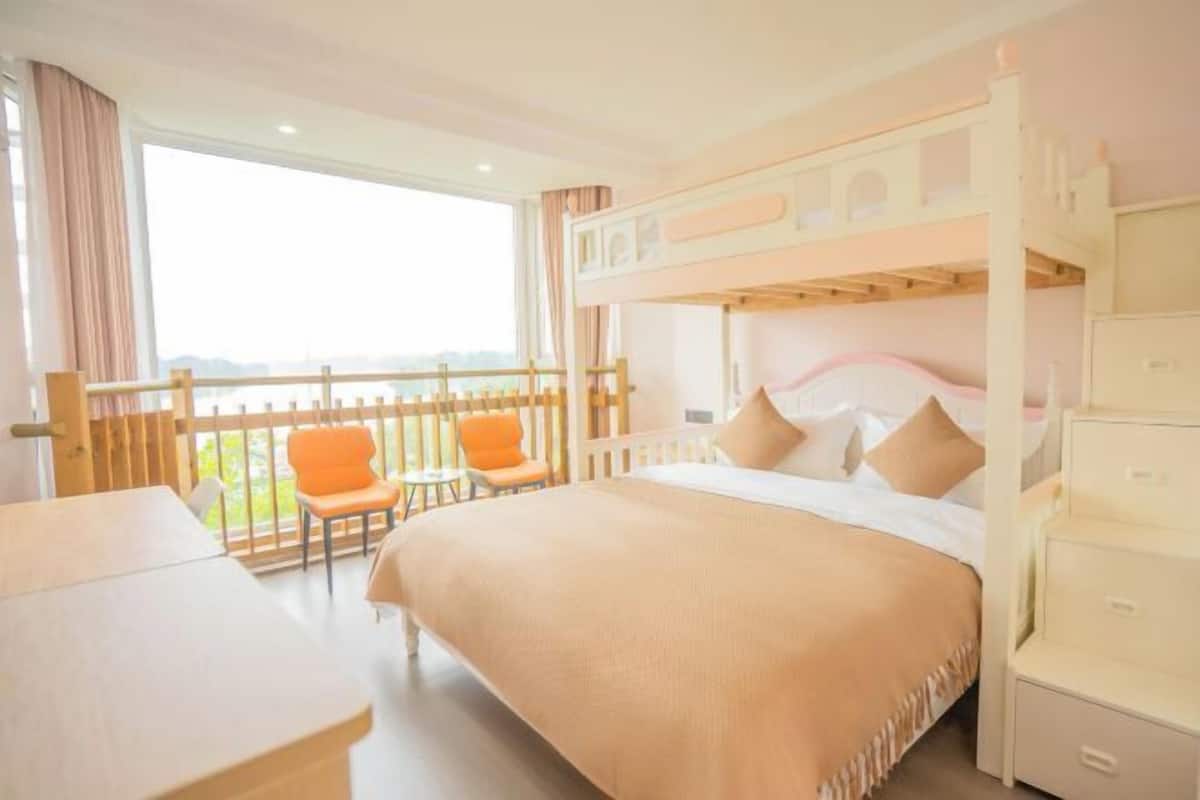 Een slaapkamer met stapelbed, balkon, bureau en twee stoelen.