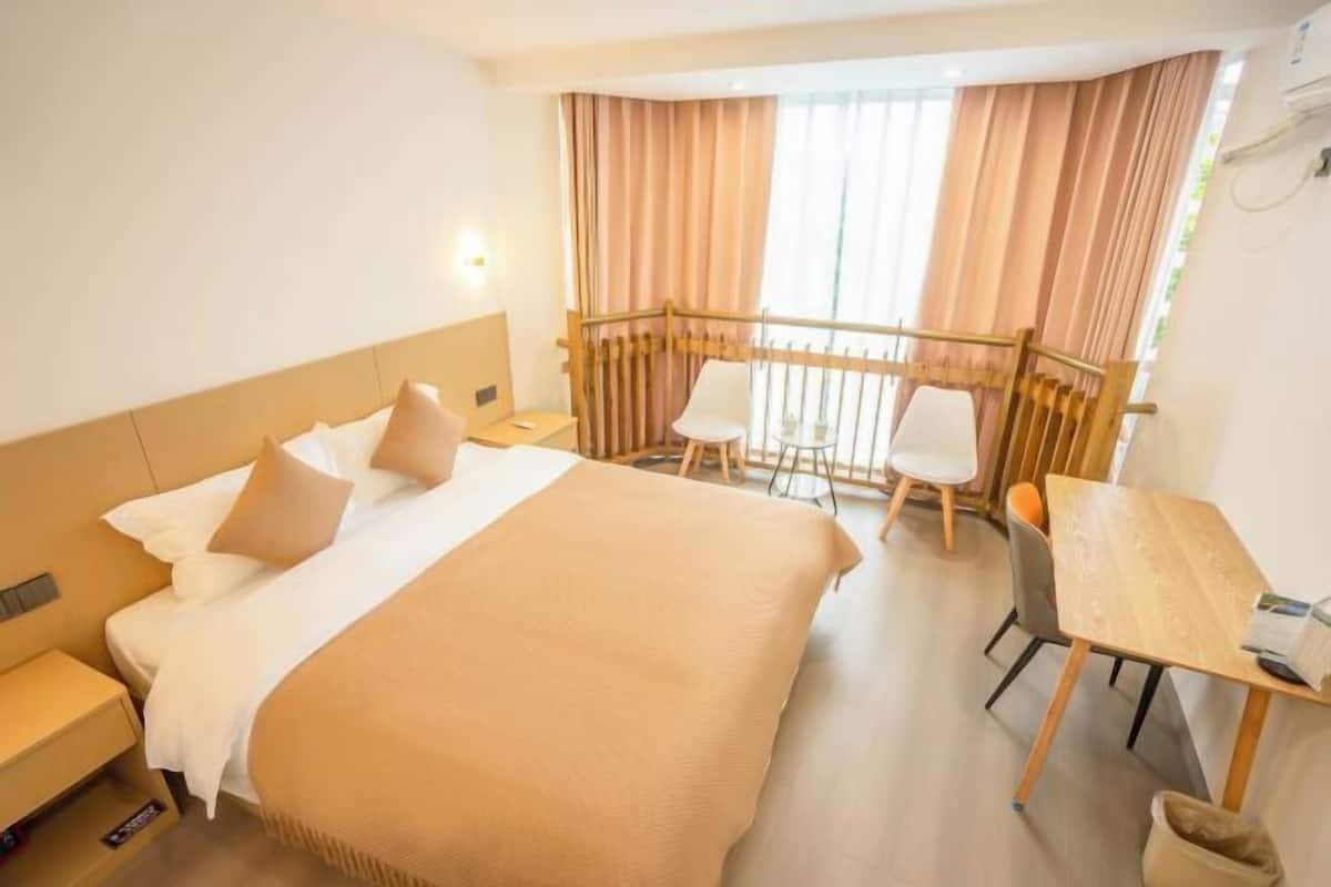 Een hotelkamer met een bed, een bureau en een balkon met gordijnen.