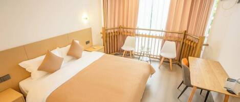 A hotel room with a bed, a desk, and a balcony with curtains.