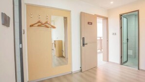 Een hotelkamer met een houten deur, een spiegel en een douchecabine van glas.