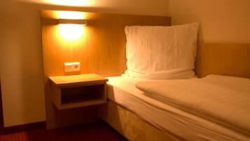 Ein Hotelzimmer mit einem Einzelbett, einem Nachttisch und einer Wandleuchte.