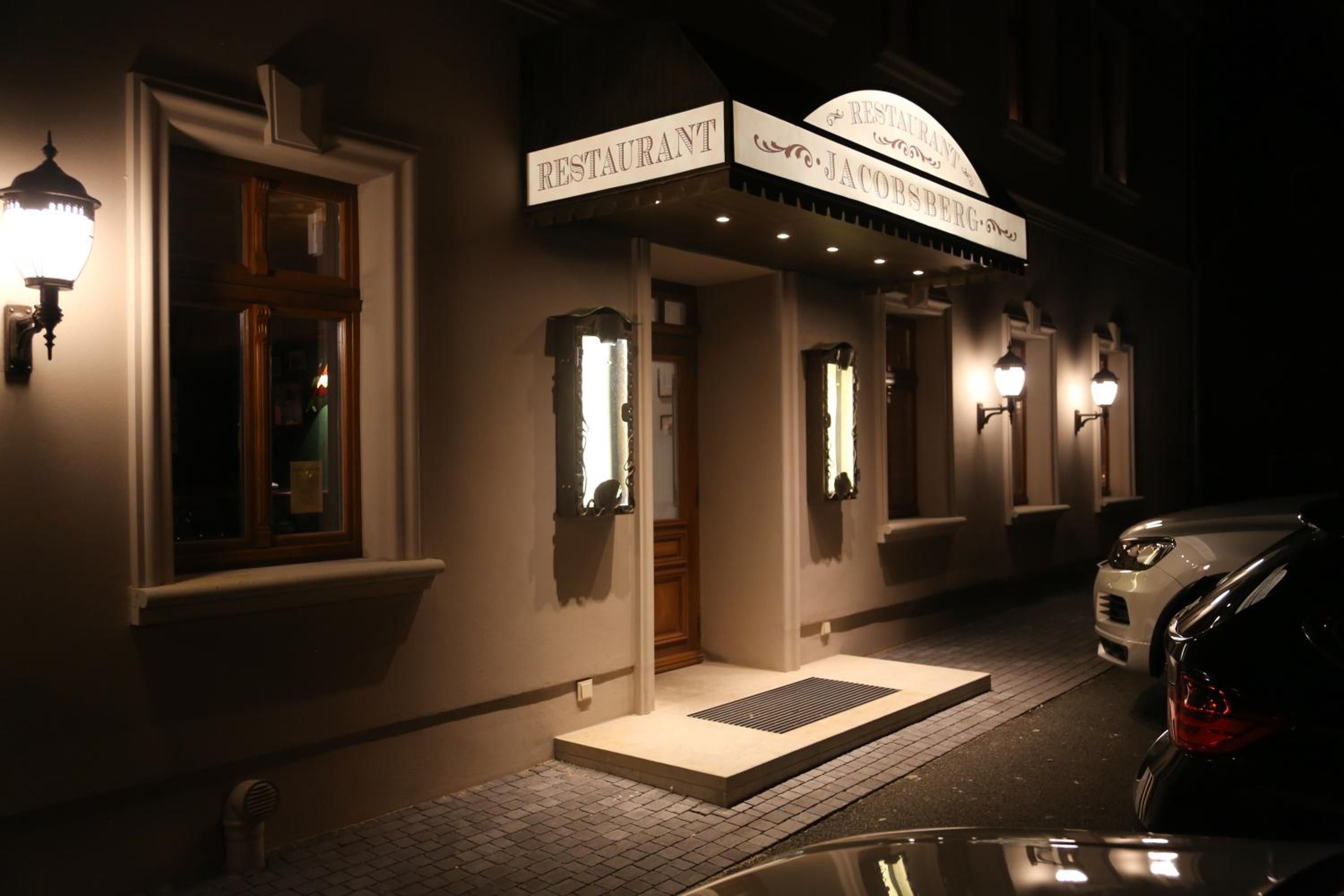 Ein Gebäude mit einem Schild, auf dem 'RESTAURANT JACOBSBERG' steht, und ein abgestelltes Auto.