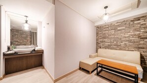 Casa de banho moderna com lavatório branco, espelho e um banco de madeira.