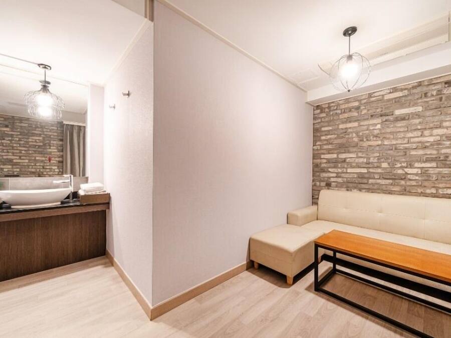 Un baño moderno con un lavamanos blanco, espejo y un banco de madera.